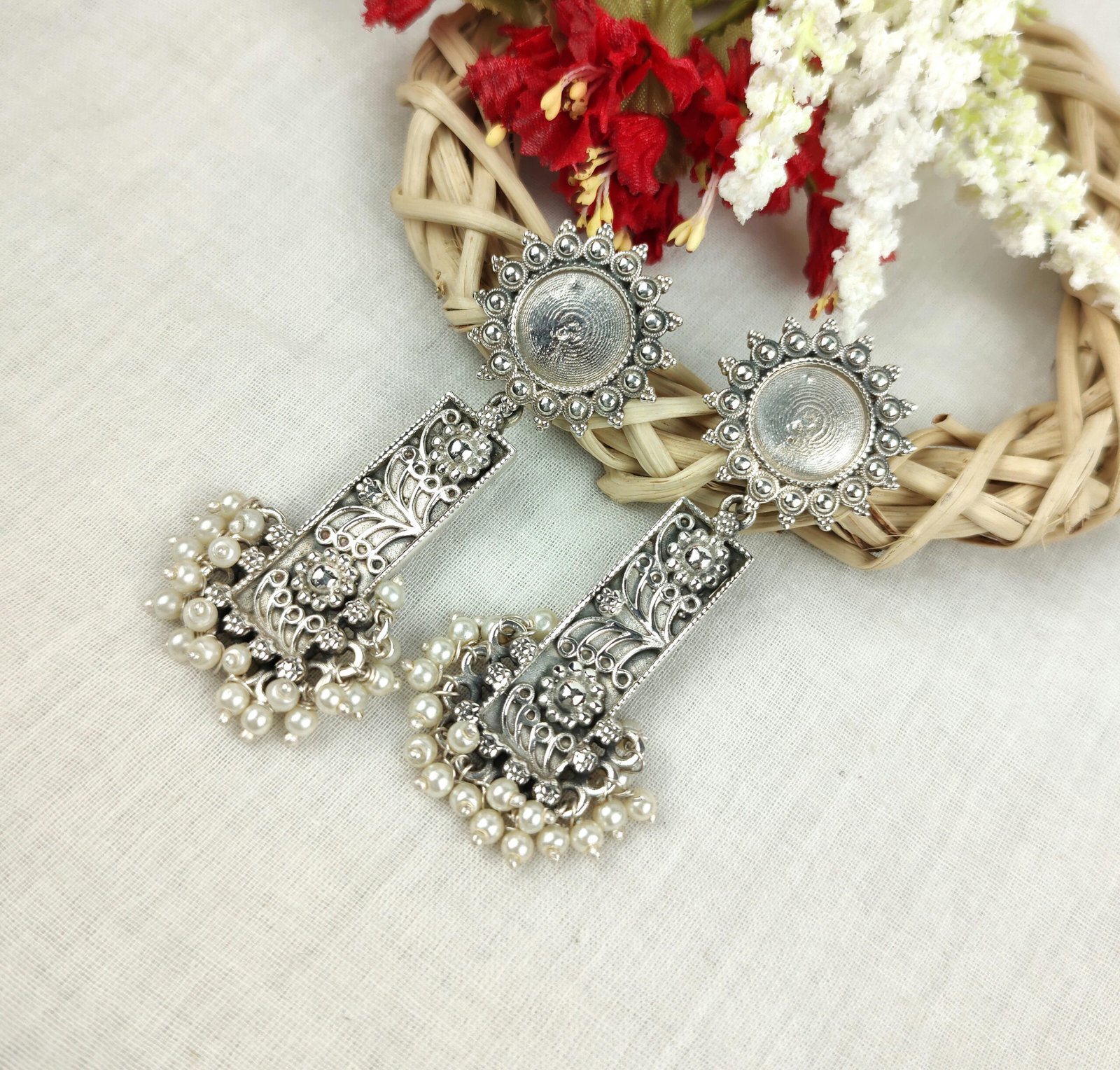 Detailed close-up of vintage oxidized silver earrings with pearl accents on a textured background.